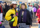 2 people at the International Women's Day in Berlin 2019 with the CO-WC sign and a poster with the inscription "Scheiß Patriarchat Elendiges."