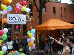 Person points with her finger at the CO-WC info booth at the Lesbian and Gay City Festival in Berlin.