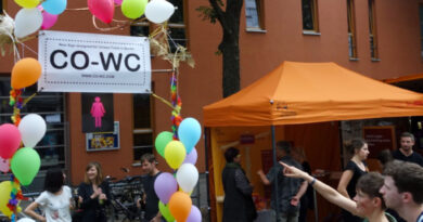 Person points with her finger at the CO-WC info booth at the Lesbian and Gay City Festival in Berlin.