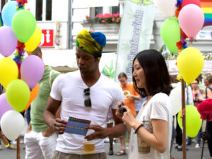 Shinhee Chae with a festival-goer at the CO-WC information booth surrounded by balloons.