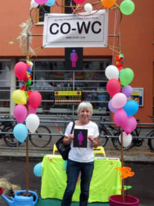 Elderly person stands in the information booth with the CO-WC sign.