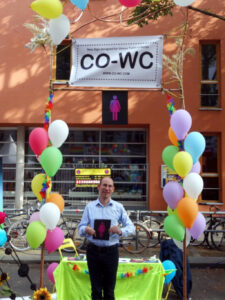 One Person in front oft the info booth holding the CO-WC sign in both hands.