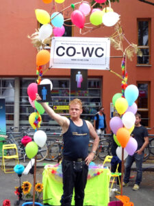 Person poses in front of CO-WC info booth and holds the sign high in the air.