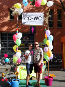 Two people perform with the CO-WC sign at the information booth.